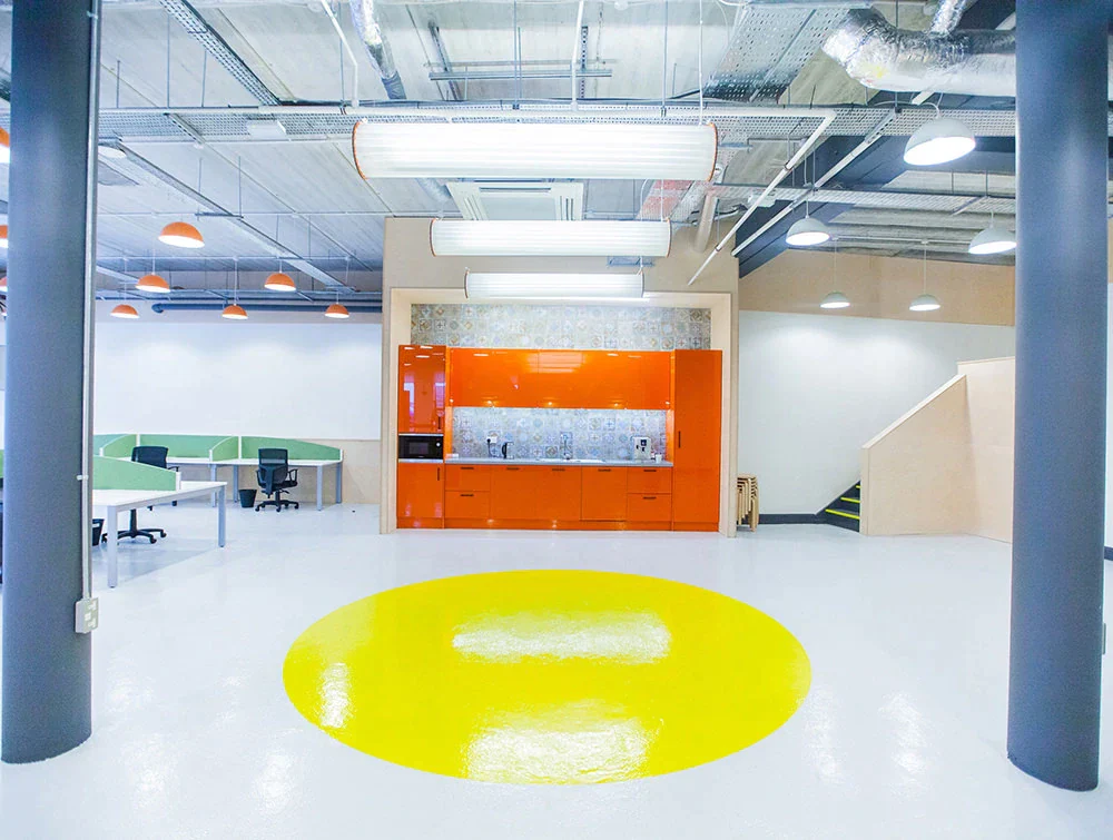 Open-area-with-orange-kitchenette-and-yellow-circle-on-floor