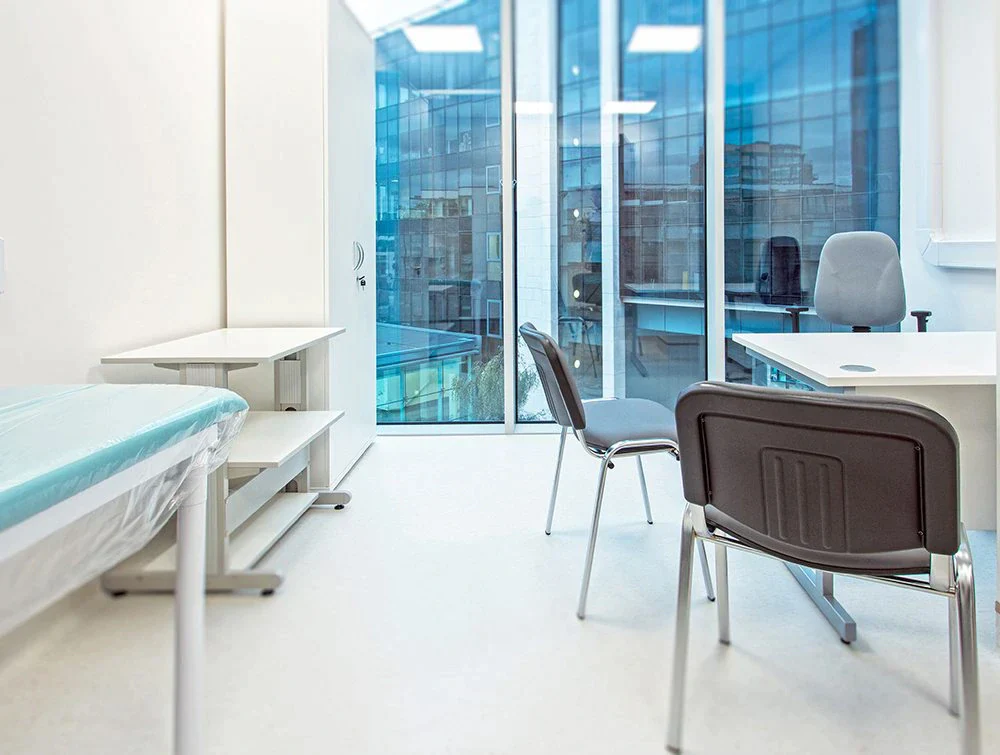 White-desk-and-multiple-grey-chairs-in-plain-white-room